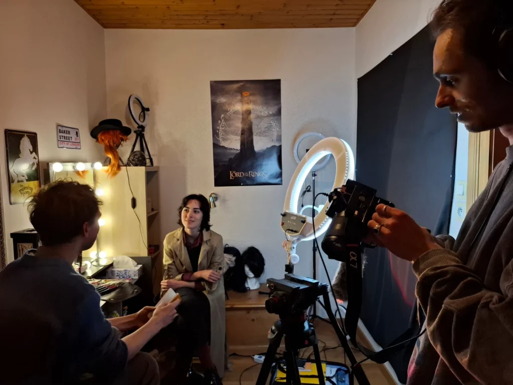 Trois personnes dans une pièce en discussion avec un équipement photographique.