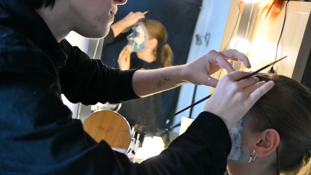 Math David Makeup applique un maquillage bleu et blanc sur le visage d'une modèle.