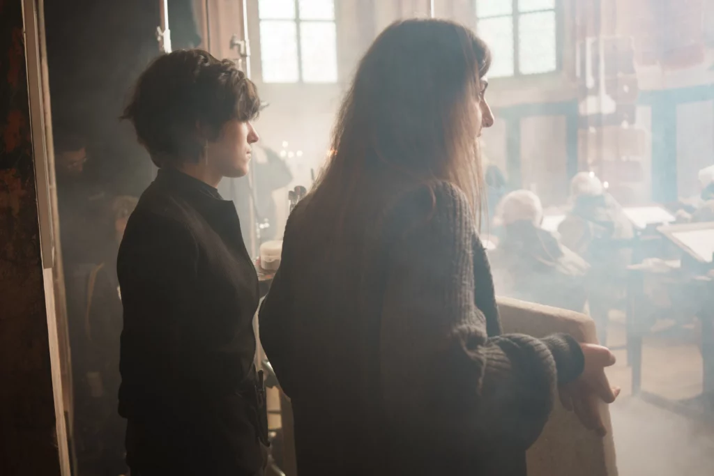 Math David Makeup et une femme se tenant sur le côté du plateau de tournage.