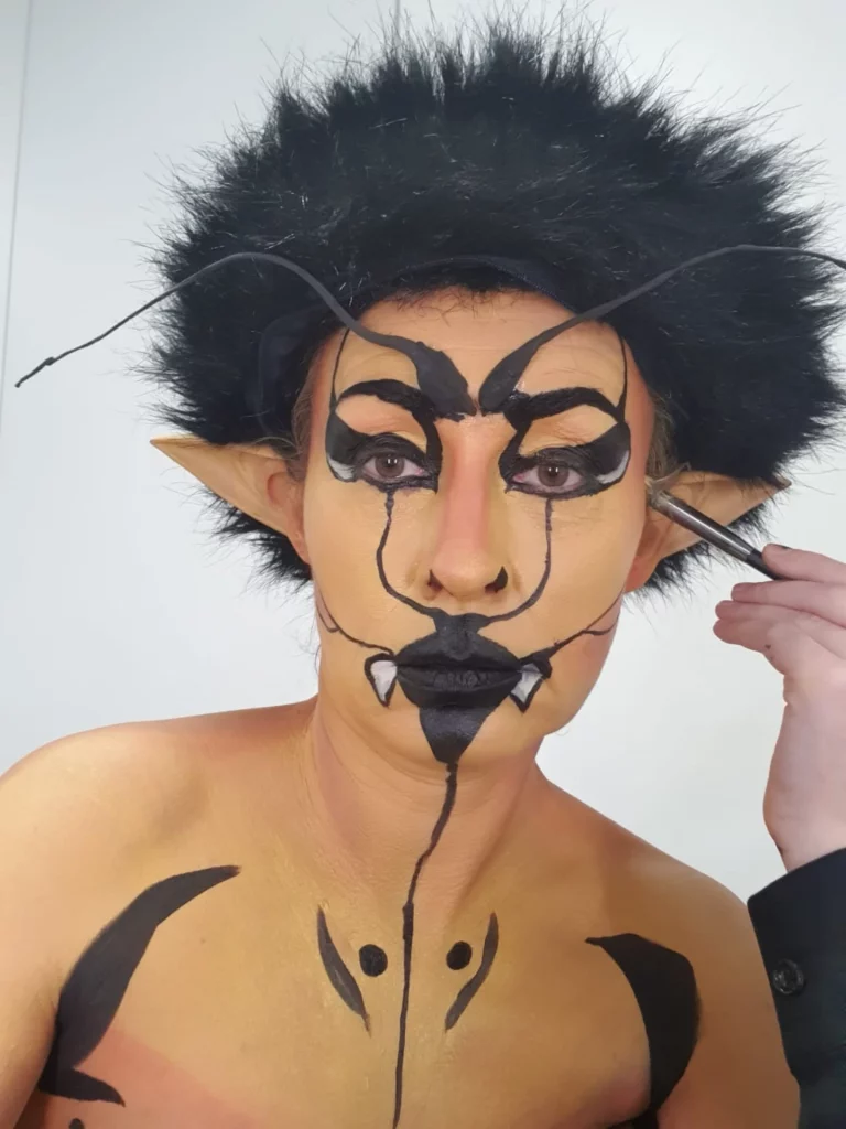 Modèle maquillé en guêpe, en train de se faire peindre l'oreille.