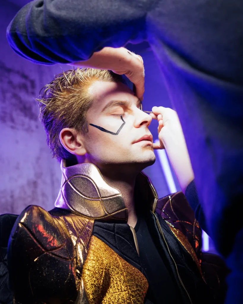 Contre-plongée du visage d'un homme en train de se faire maquiller le visage.