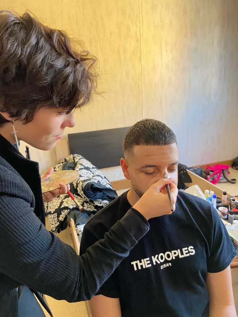 Math David Makeup réalisant un vieillissement du visage sur un modèle masculin pour un tournage.