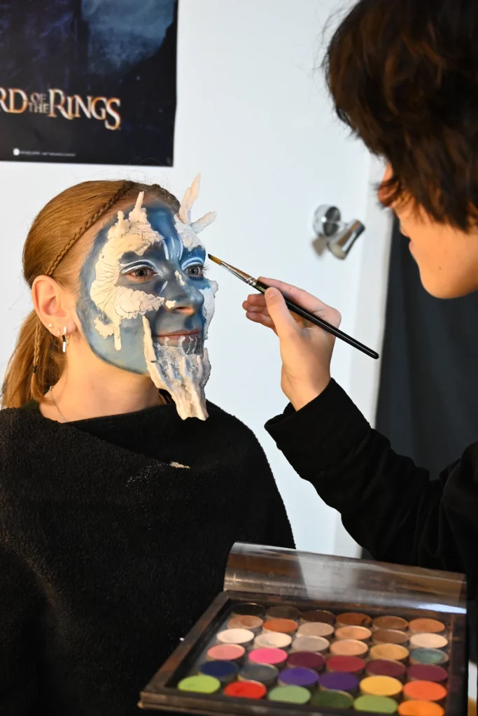 Jeune femme avec un maquillage artistique et Math David Makeup réalisant les dernières retouches.