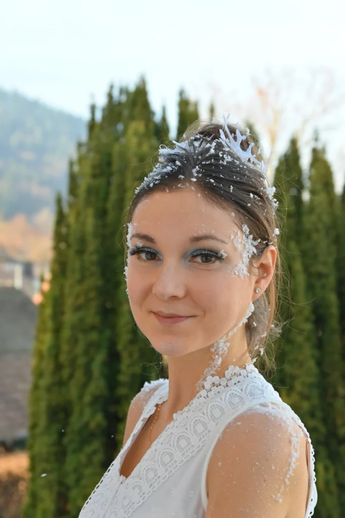 Modèle posant pour une photo, arrière plan flou, maquillage naturel mais comprends fausse neige