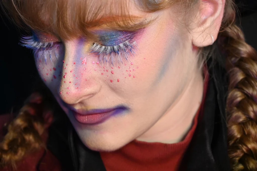 Gros plan sur le visage d'une femme au maquillage coloré avec des faux-cils.