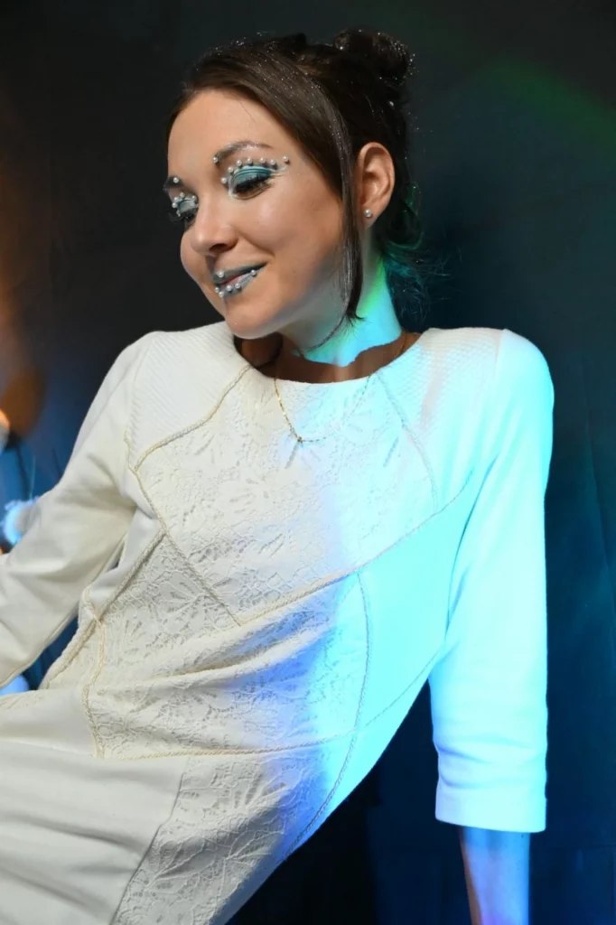 Femme vêtue d'une robe blanche texturée, maquillée des yeux en argent et des lèvres bleues.