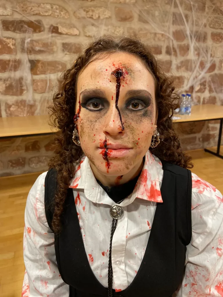 Modèle de face avec un maquillage SFX, avec du faux sang et un impact de balle dans le front