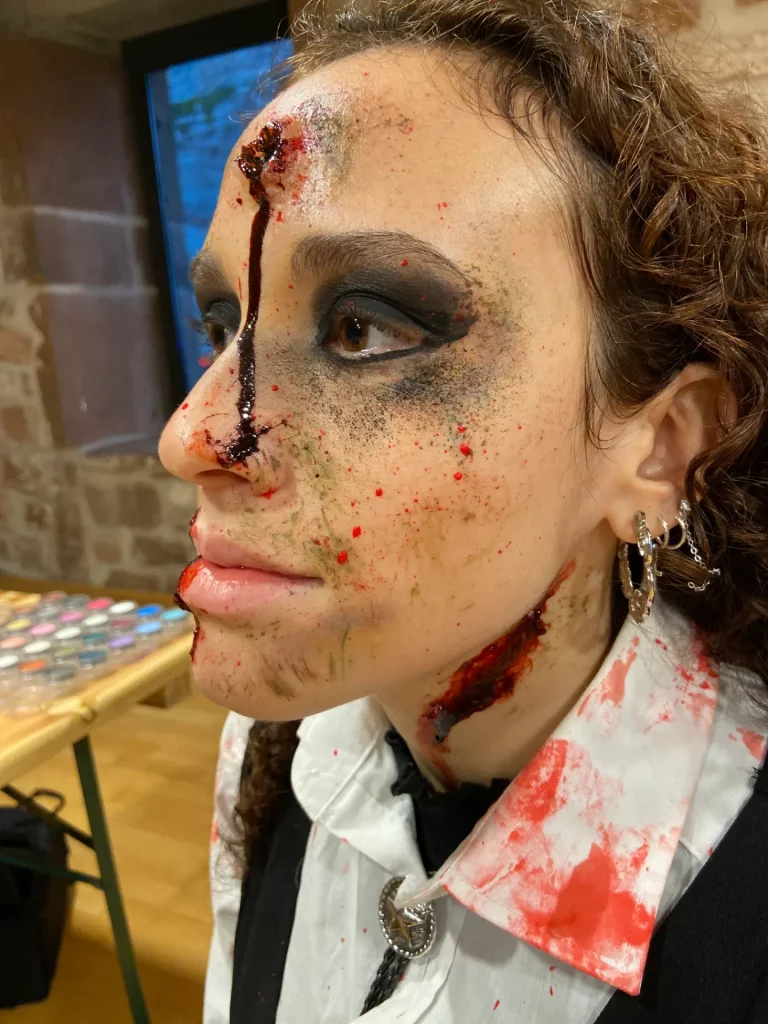 Gros plan sur le profil d'une modèle, avec maquillage SFX d'un impact de balle dans le front et du sang