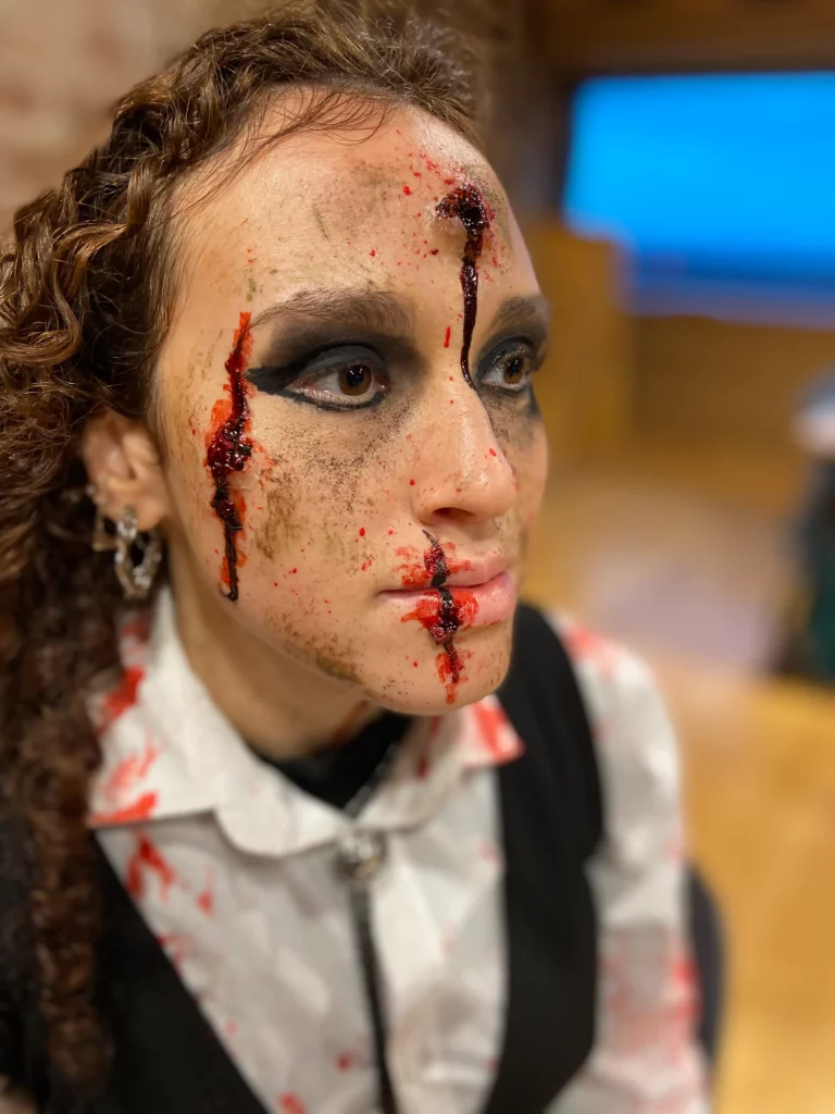 Gros plan sur le visage d'une modèle, avec du faux sang et un impact de balle
