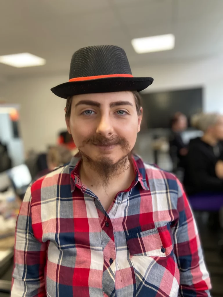 Modèle avec un maquillage SFX de transformation masculine avec pose de fausse barbe