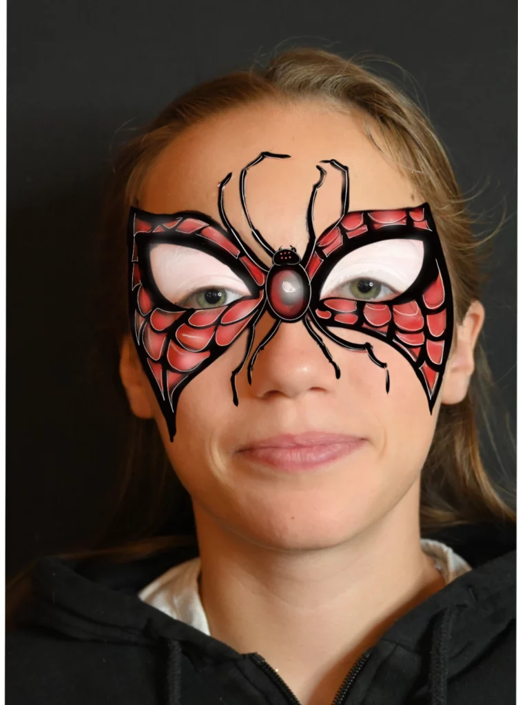 Maquillage spiderman sur une fille, avec des motifs rouges et noirs en forme de toile d'araignée sur les yeux et le nez.