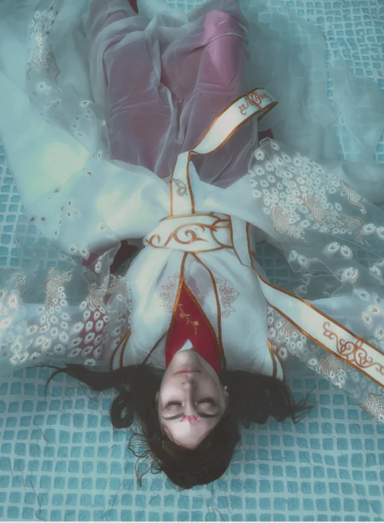 Jeune femme en cosplay japonais couché dans l'eau, maquillage du visage léger.