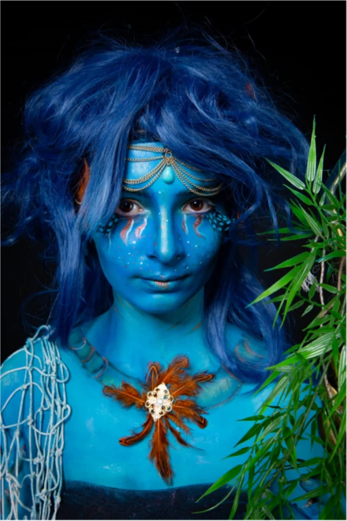 Portrait d'une jeune femme avec une peau bleu, portant un accessoire en forme de filet et un collier de plumes.