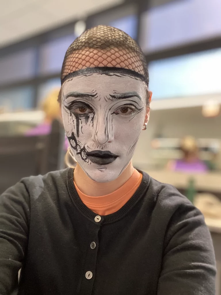 Une personne au visage monochrome, ressemblant à un personnage de bande dessinée, portant une wig cap.