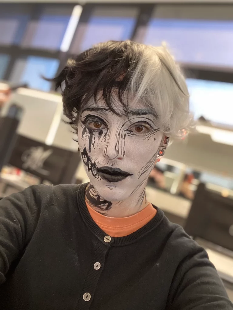 Femme au visage monochrome, ressemblant à un personnage de bande dessinée, avec une perruque bicolore noir et blanc.